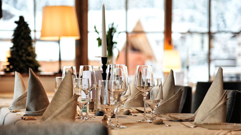 Gedeckter Tisch mit Weingläsern und Servietten, im Hintergrund Fenster mit Blick auf den Winter